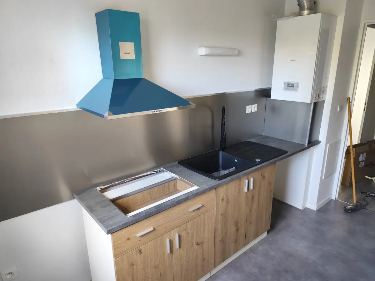 Pose de cuisine : meubles bas façade bois, plan de travail, évier noir et crédence en inox