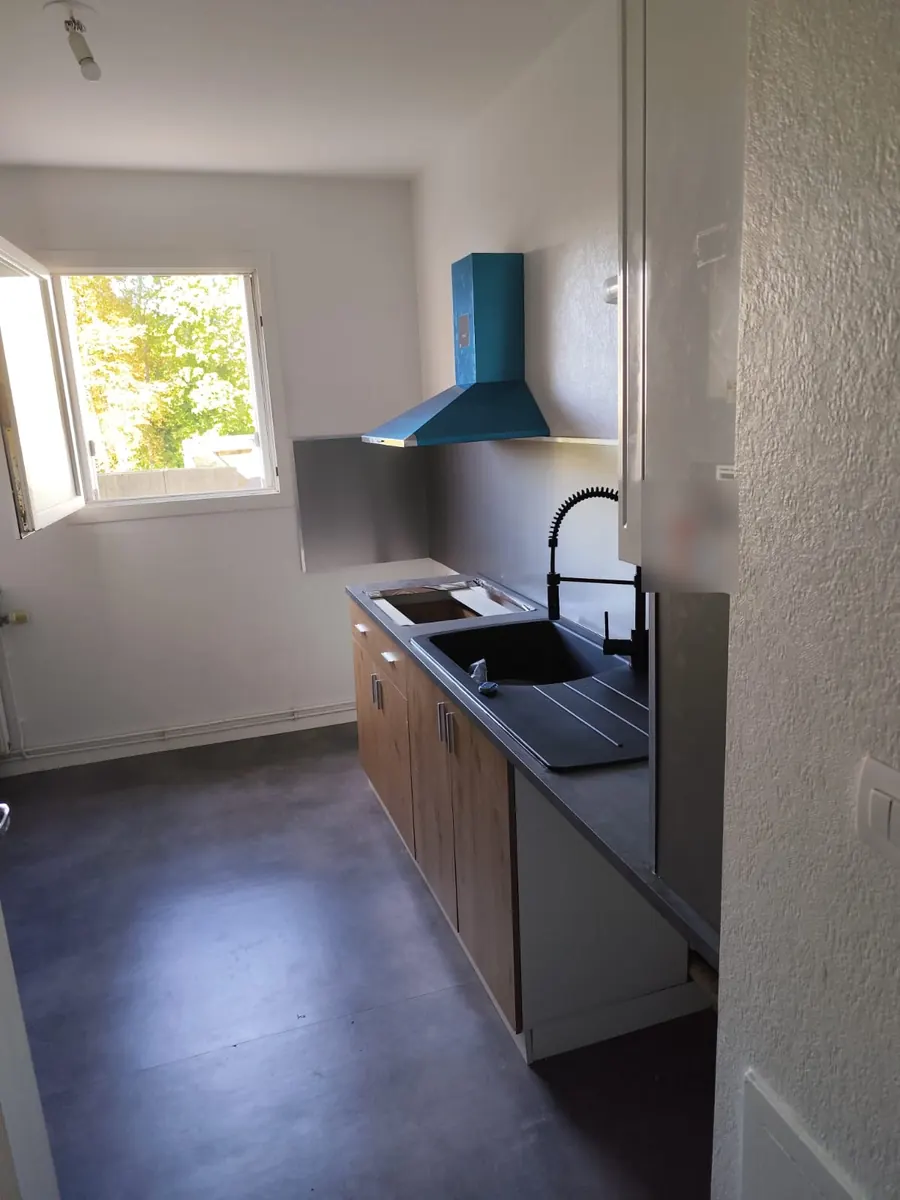 Pose de cuisine vue de côté : meubles bas façade bois, plan de travail et évier